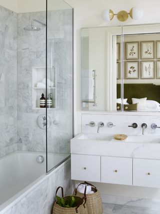 marble bathroom with shower over tub, wall mounted double basin vanity, mirror, ensuite