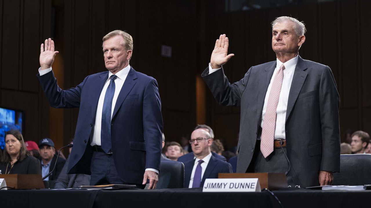 Two men in suits raising their hands getting sworn in during a Senate hearing