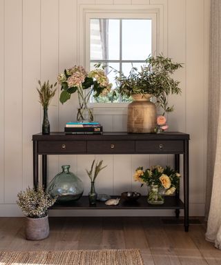 hallway with white wood paneled walls and console table with flowers