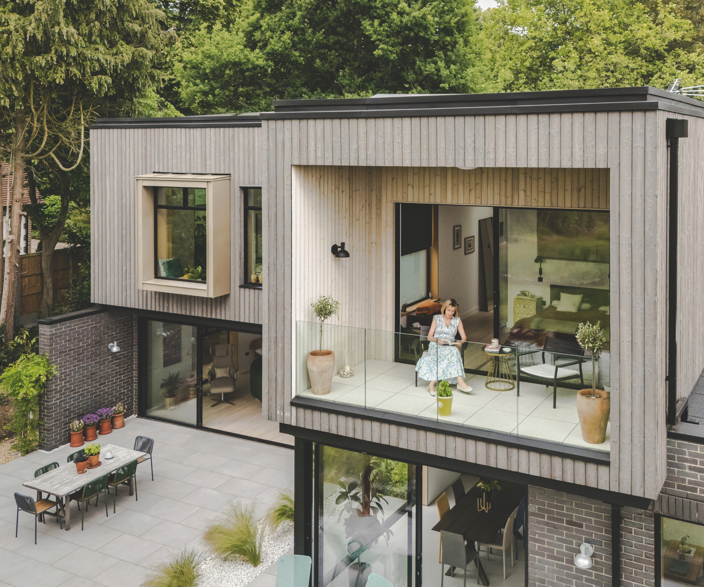 Exterior of house with woman sitting on patio outside room