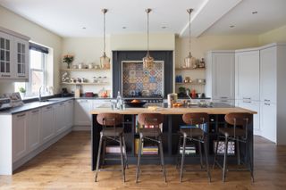 A kitchen with white cabinets, a large kitchen island, open shelving and a tiled backsplash