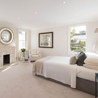 bedroom with white walls fireplace and mirror on wall