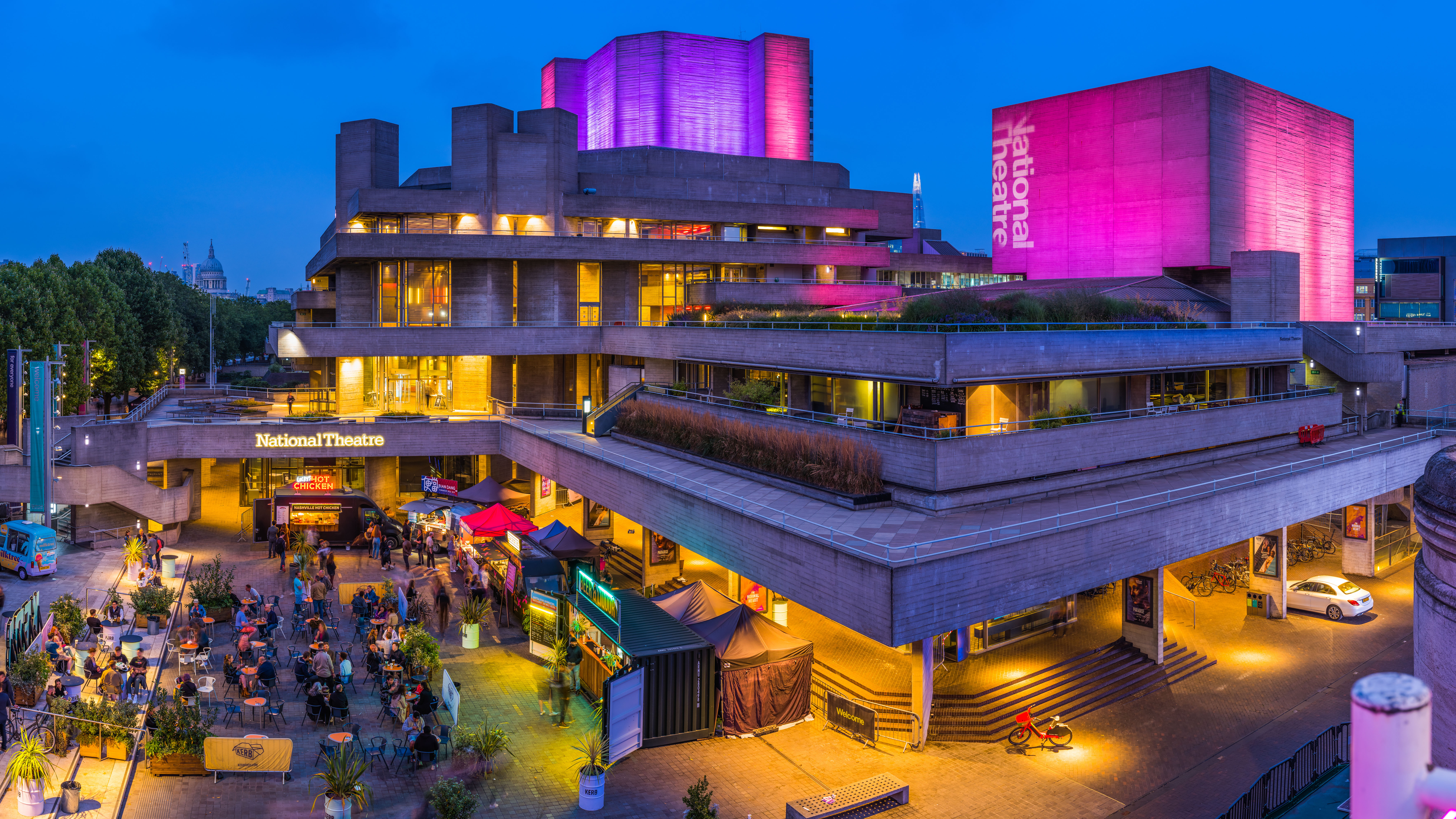 Exterior of the National Theatre at nigh, up-lit in blue and pink