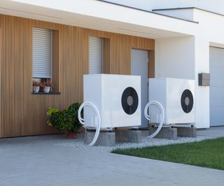 modern wood clad house with white render wall and two exterior heat pump units
