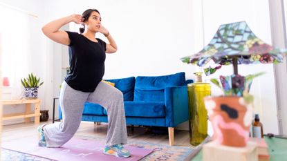 A woman performing a reverse lunge during a no-equipment home workout 