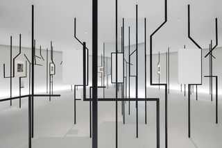 Black metal bars connect the ceiling and floor, some displaying artwork