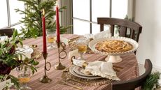 Christmas table with red gingham tablecloth, white napkins, gold napkin rings and red taper candles