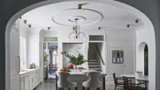A dining room in all cream times, with an arch-entry that used to be a wall