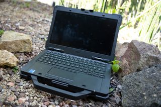 A black Dell Latitude 7330 Rugged Extreme laptop sitting on a rocky surface