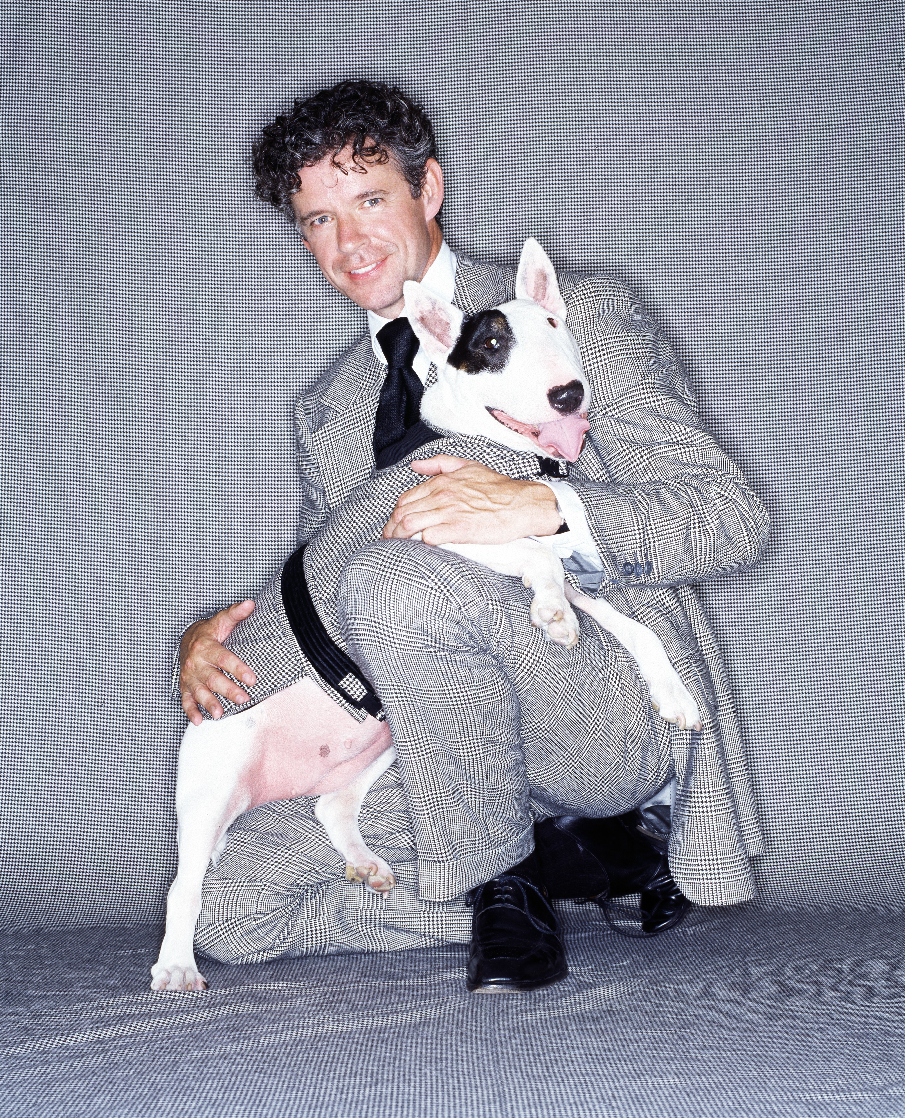 Man in a grey check suit holding an English bull terrier
