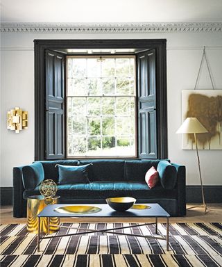 Grey room, black window frame and shutters, blue velvet sofa