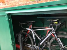 Bike storage shed doors open with two bikes inside 