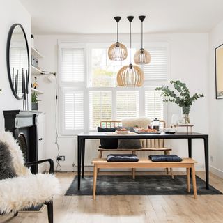 White dining room with shutter and wooden pendant light