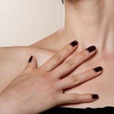 woman with black square nails against her chest