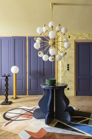 A transitional space with purple-blue painted doors and yellow walls
