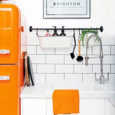 Fresh orange and white kitchen with orange smeg fridge