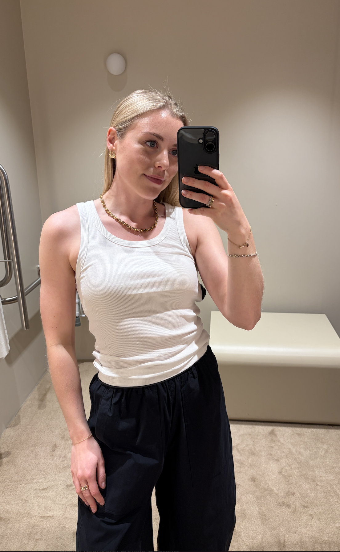 Florrie wearing white tank top and black trousers