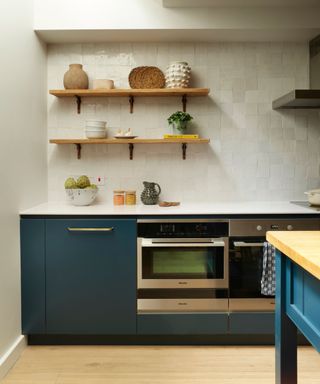 A white kitchen with blue cabinets and open shelving