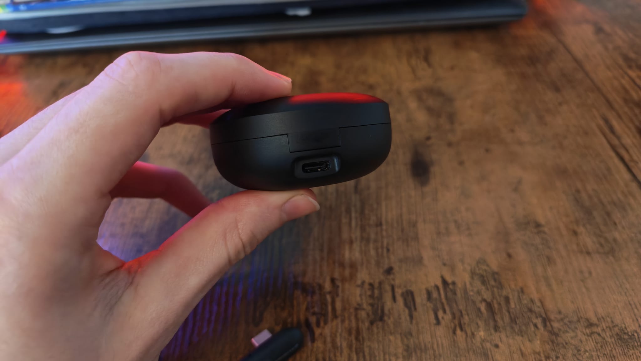 A reviewer showcasing the USB port on the PrismXR Vega T1 earbuds case