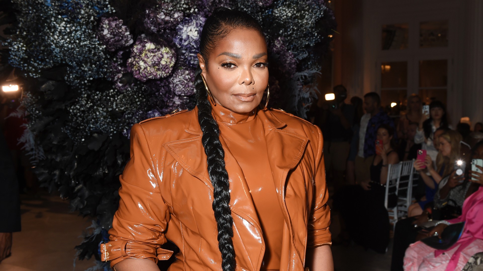 a black woman with dark hair wearing a long braid and a tan coat