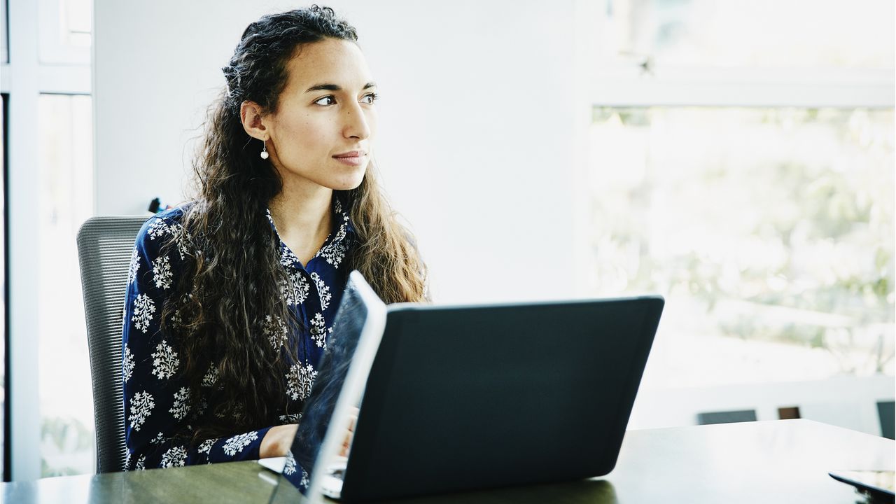 A woman sits in front of her laptop contemplating her retirement income plan.