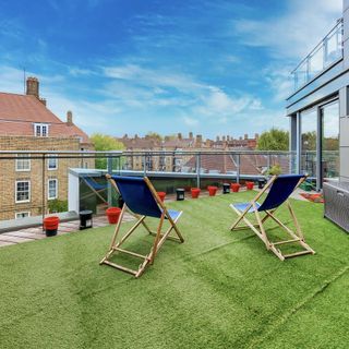 Terrace with blue deckchairs, astro turf and a view of london