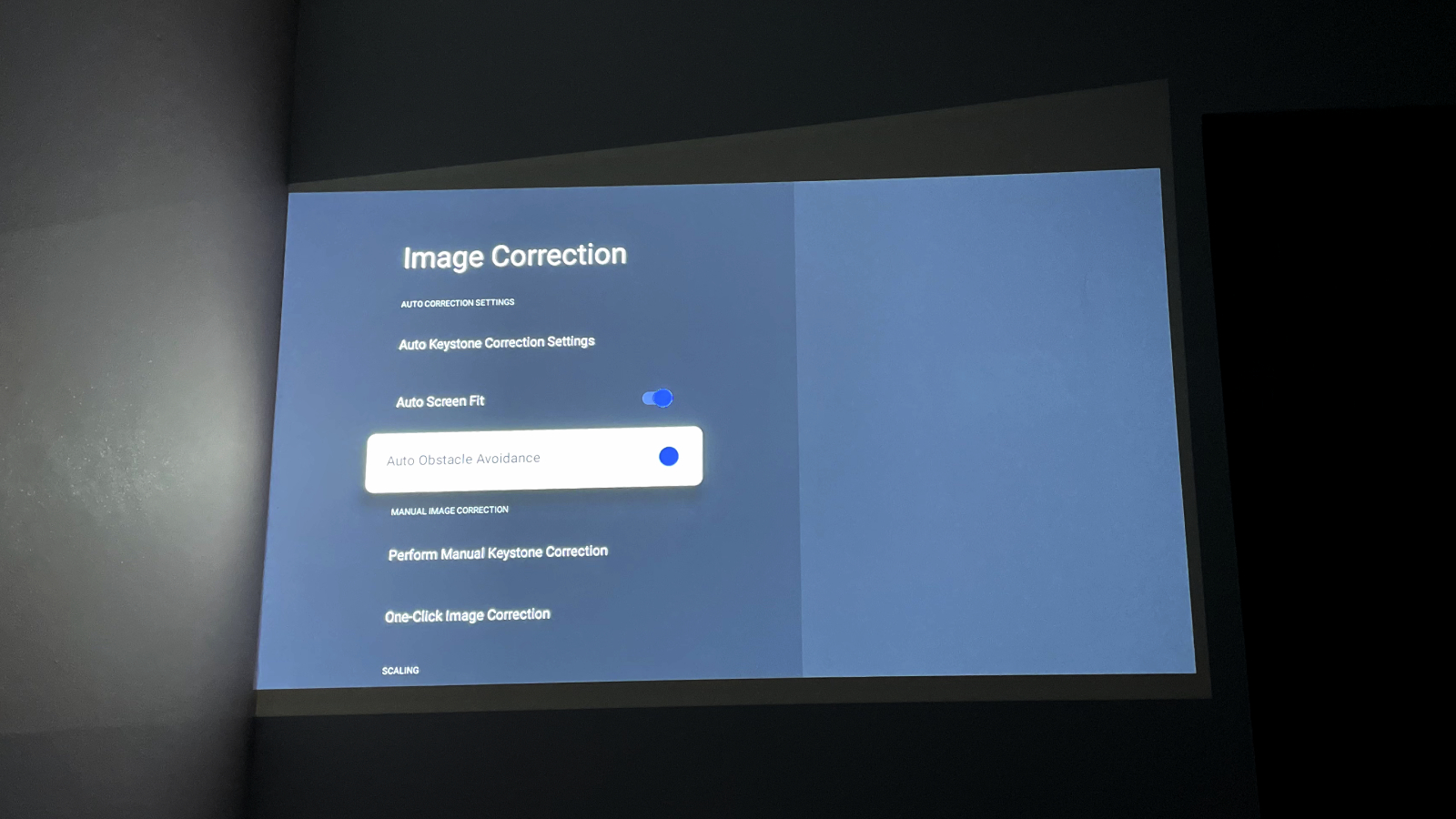 Image shows the image correction settings screen projected onto a light gray wall in the dark.