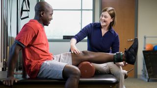physical therapist assisting man with leg exercise