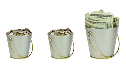 Three budgeting buckets lined up, two filled with coins and one with cash.