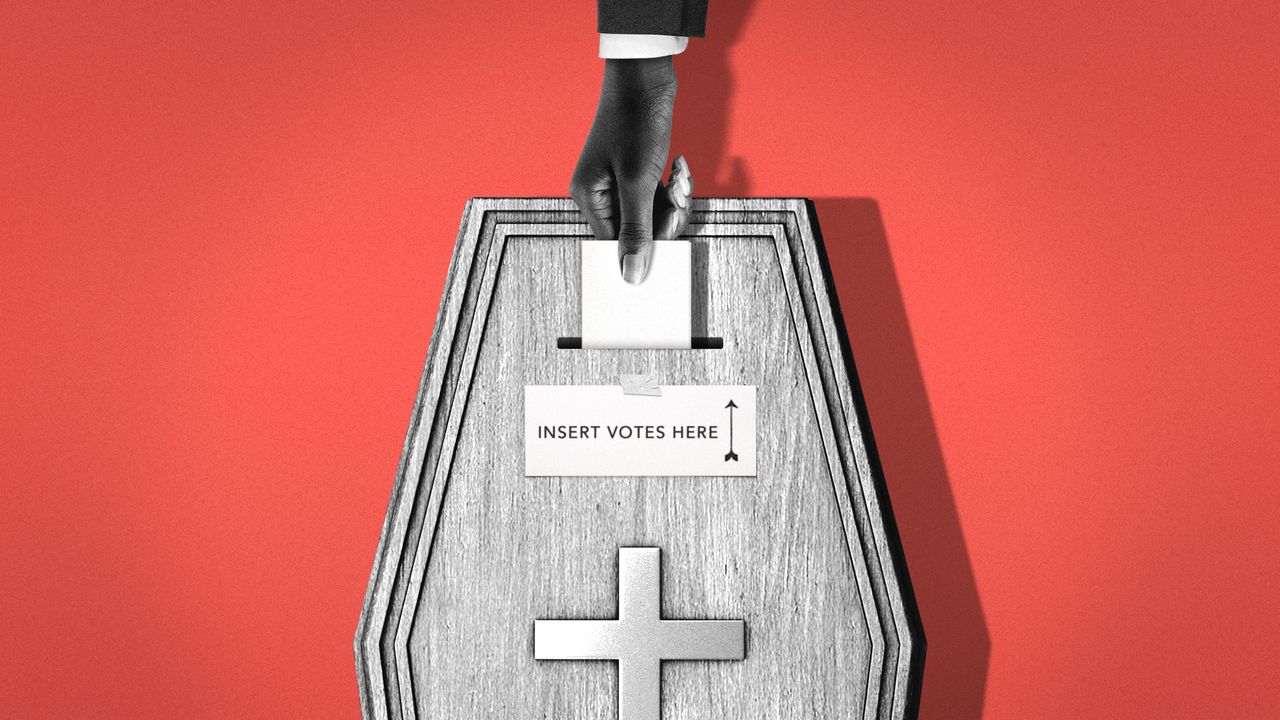 Hand placing vote in a coffin-shaped ballot box