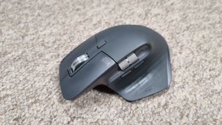 A Logitech MX Master 3S mouse on carpet, with a bright white light above it