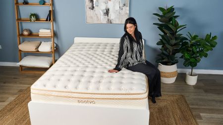 A tester sits on the edge of the bet fiberglass-free mattress, the Saatva Classic