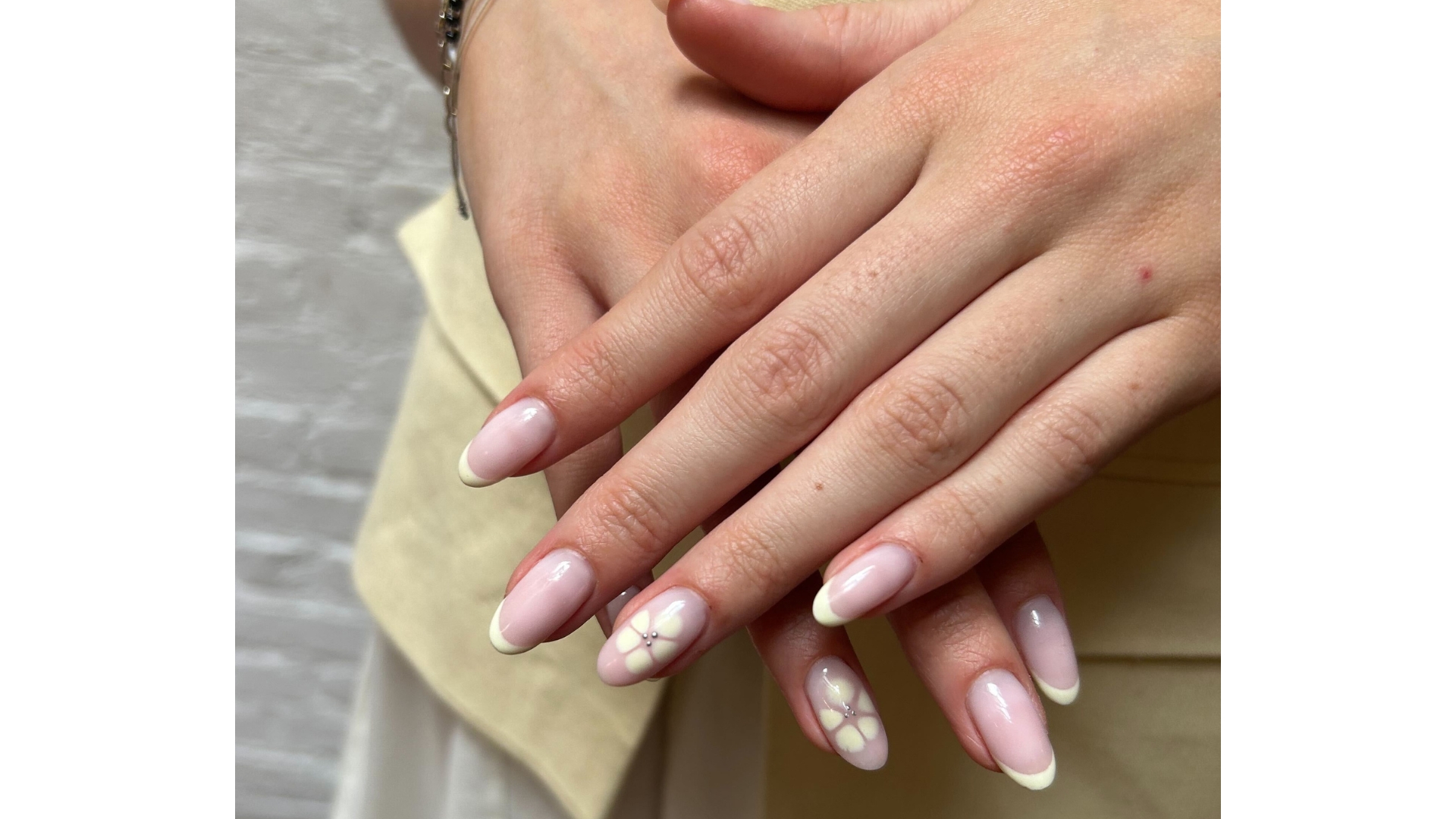 A close-up of Digital Beauty Writer, Sennen Prickett's hands, which are pictured with lemon French tip and flower nails