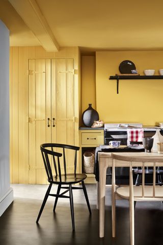 A yellow color drenched kitchen with a wooden dining set