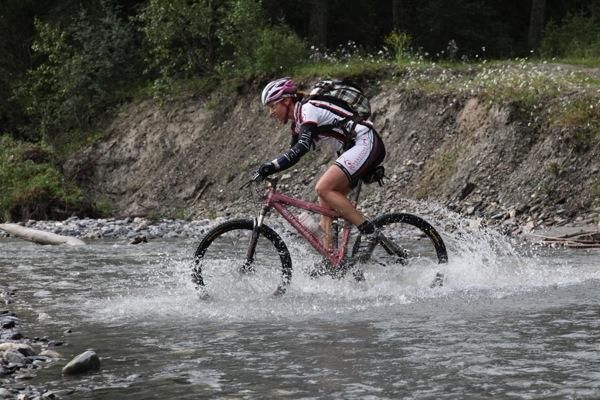 A TransRockies rider drives through a river on stage 5