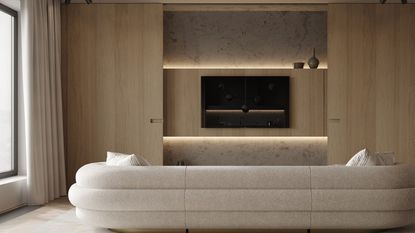 A TV mounted on a wall in a sleek wooden unit, with a large white sofa in front of it 