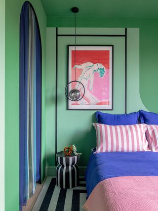 A bedroom with bright green walls, and blue and pink bedding