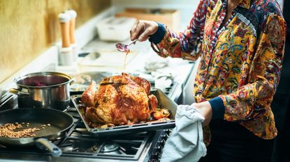 Woman serving a cooked turkey on a cooking dish, used to illustrate an article on woman&amp;home about &#039;How long does cooked turkey last in the fridge?&#039;