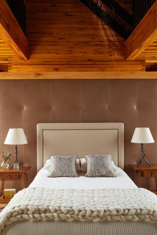 a bedroom with a brown upholstered wall and a wood clad ceiling