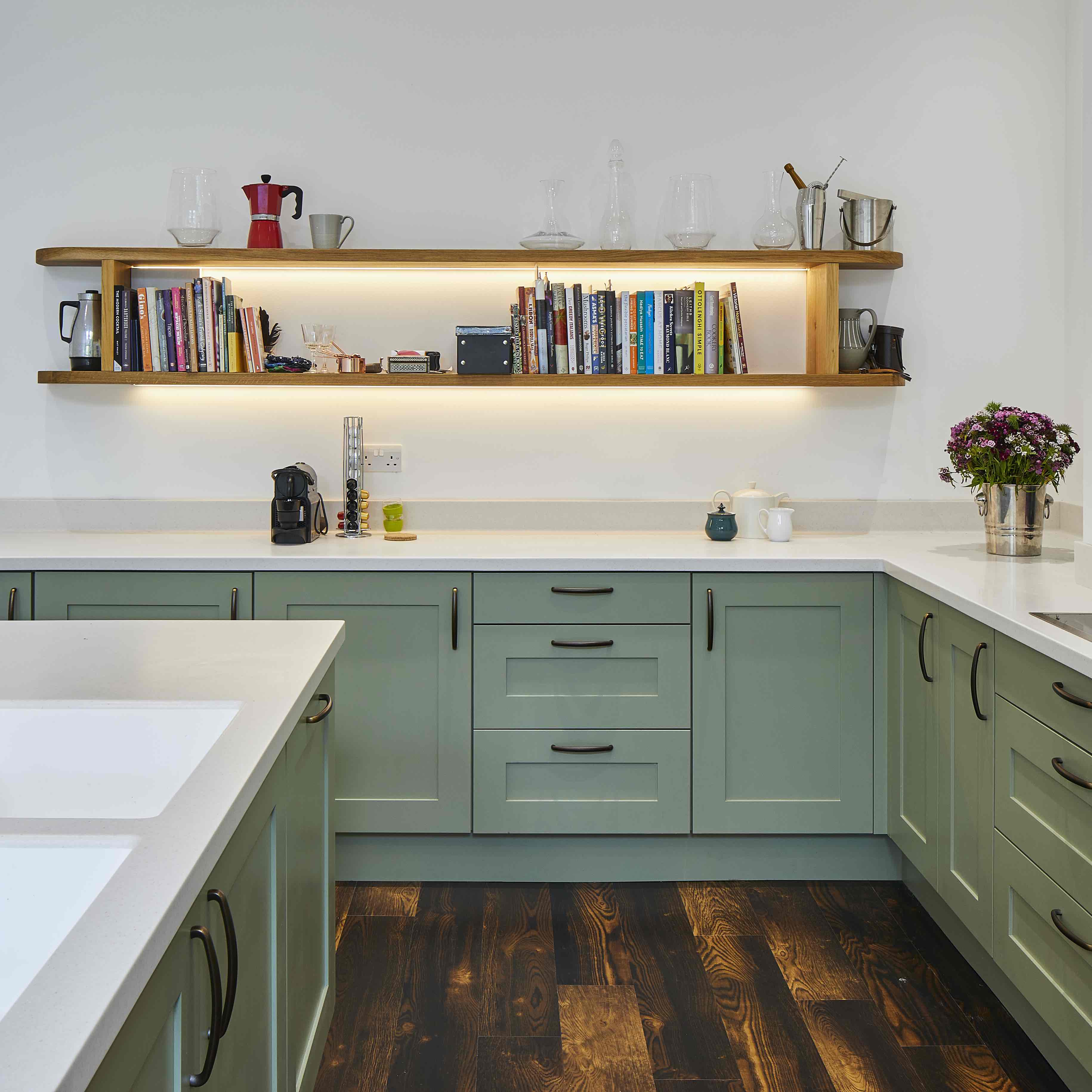 kitchen with green shaker units and illuminated shelving