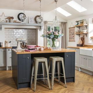White kitchen with grey kitchen island, industrial bar stools, butler sink, wood worktops and open shelving