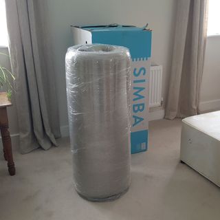 A Simba mattress vacuum packed and rolled next to its box