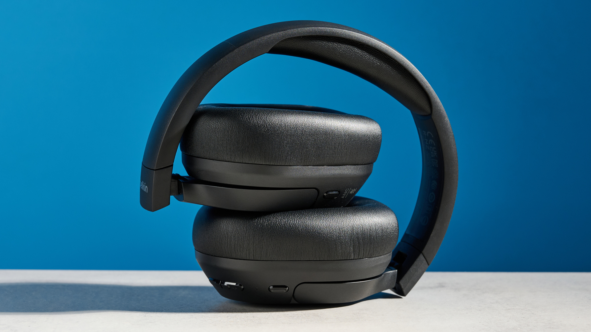 the belkin soundform isolate are a pair of budget headphones in black, with soft pillowy cups, control buttons on each cup, and ANC