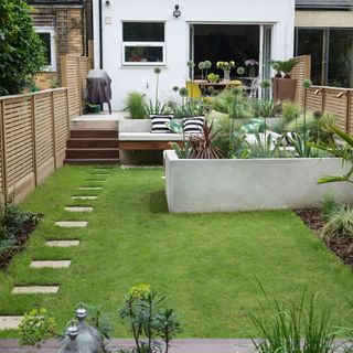 lawn in narrow garden with seating area and pathway