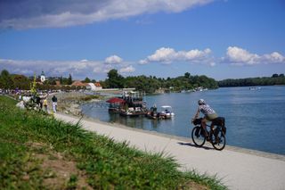 Image shows Anna cycling along the Danube river while on a gravel bikepacking trip around Central Europe.