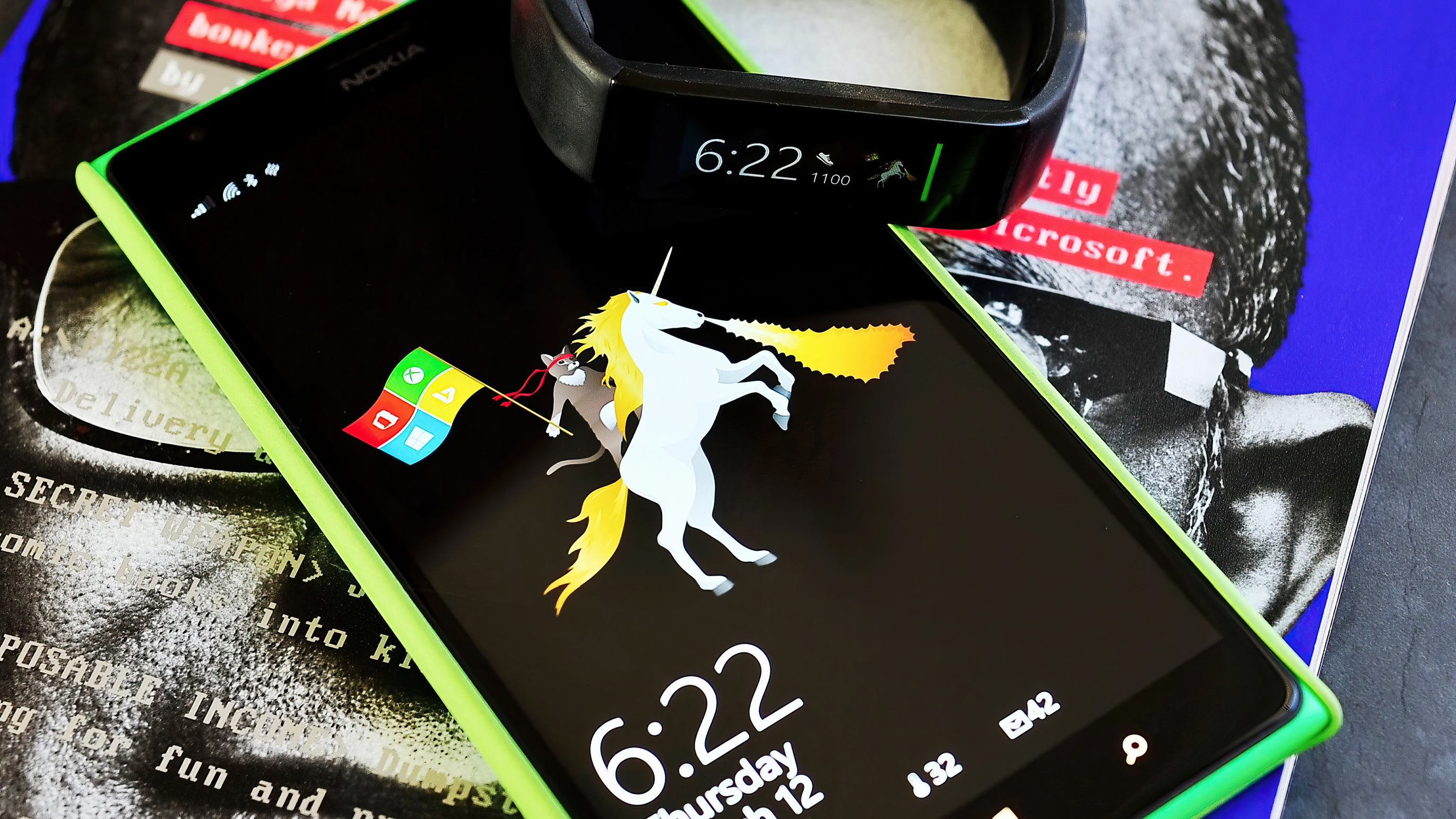 A Nokia smartphone displaying a unicorn wallpaper with a fitness band showing the time 6:22. The setup rests on a grayscale magazine page.