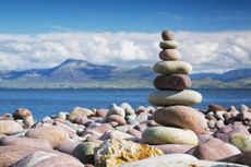 stable stack of stones on a beach with clouds on the horizon