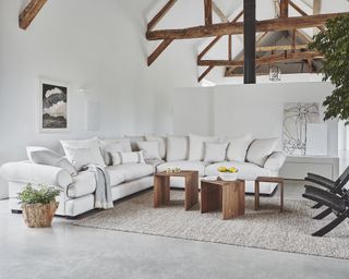 While sectional sofa with pillow back in room with ceiling open to rafters