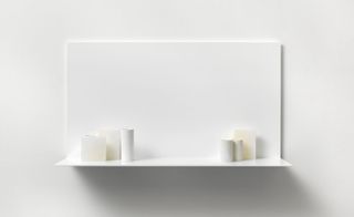 Five porcelain vessels and four alabaster blocks in white, light gray, light yellow, and light blue are set on a white shelf.