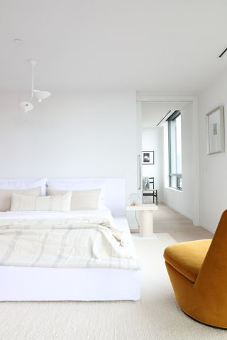 White minimalist bedroom with mustard velvet chair